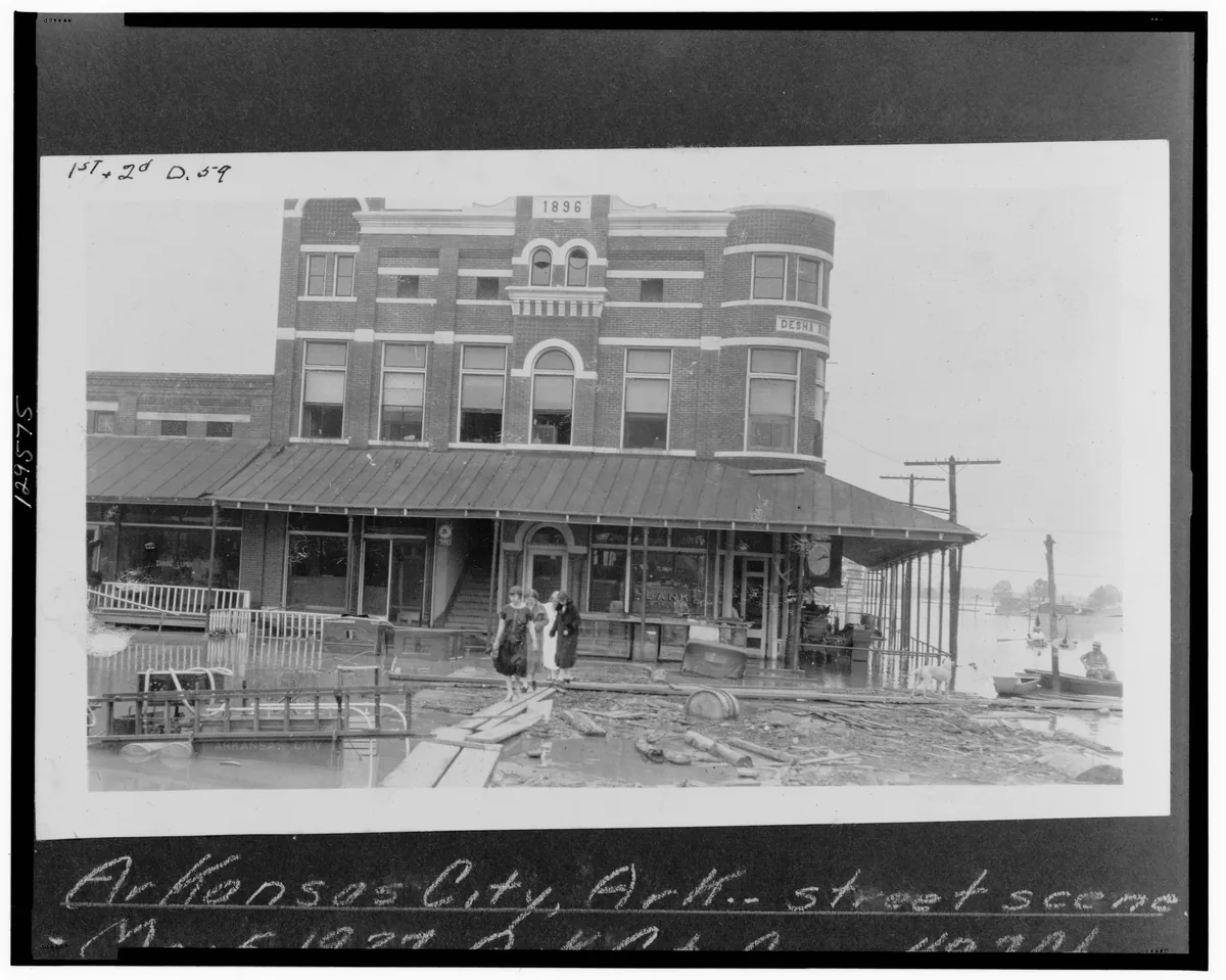 A three-story brick building with a wooden walkway and railing along its street front in Arkansas City.