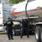 Two U.S. Customs and Border Protection officers inspect a tanker truck at the Port of Detroit, Michigan.