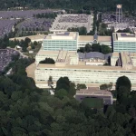 Aerial view of the CIA headquarters buildings in Langley, Virginia, surrounded by parking lots and thick woods.