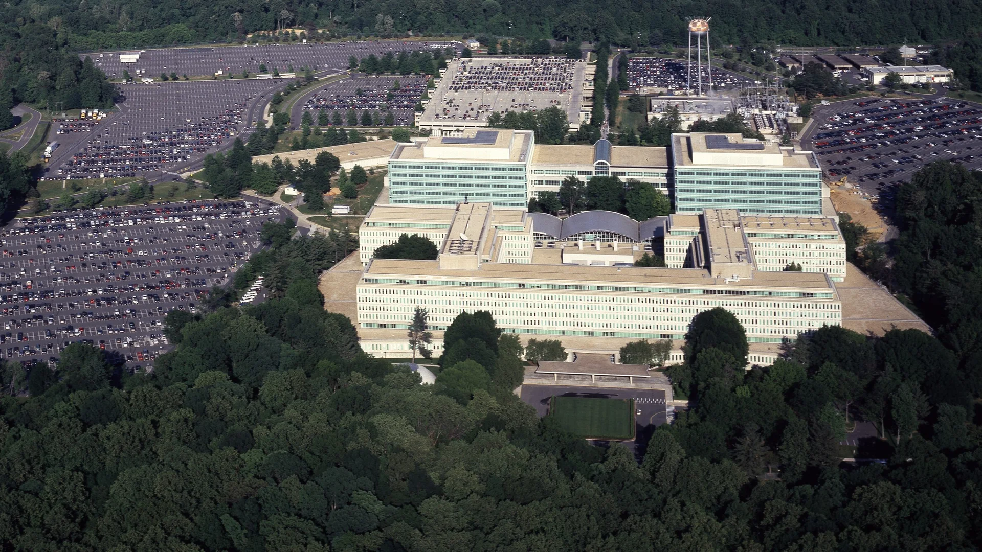 Aerial view of the CIA headquarters buildings in Langley, Virginia, surrounded by parking lots and thick woods.