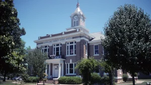 The Cleveland County Courthouse in Rison, Arkansas, a brick building with a white clock tower, framed by trees