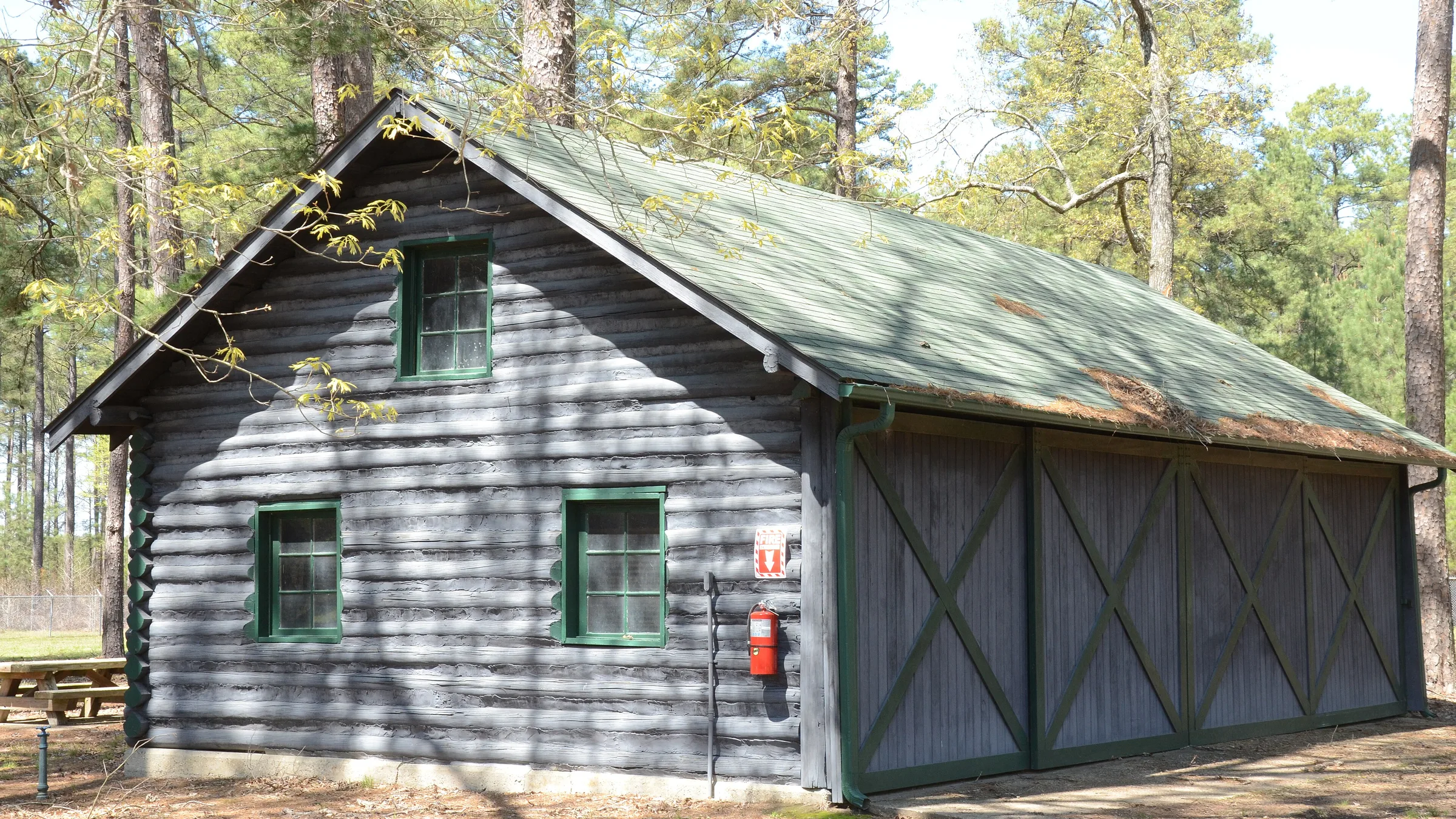 Building No. 2 at the Crossett Experimental Forest, a log-sided shed with a green metal roof among pines near Crossett, Arkansas.