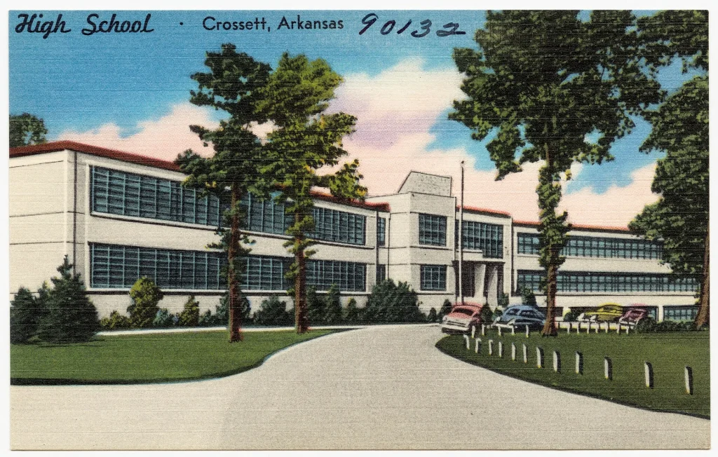 Color linen postcard of a long two-story white school building with rows of windows, behind a curving drive and trees, captioned High School, Crossett, Arkansas.