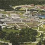 Vintage linen postcard showing an aerial view of Crossett, Arkansas, with mills, lumber yards and surrounding pine forest.