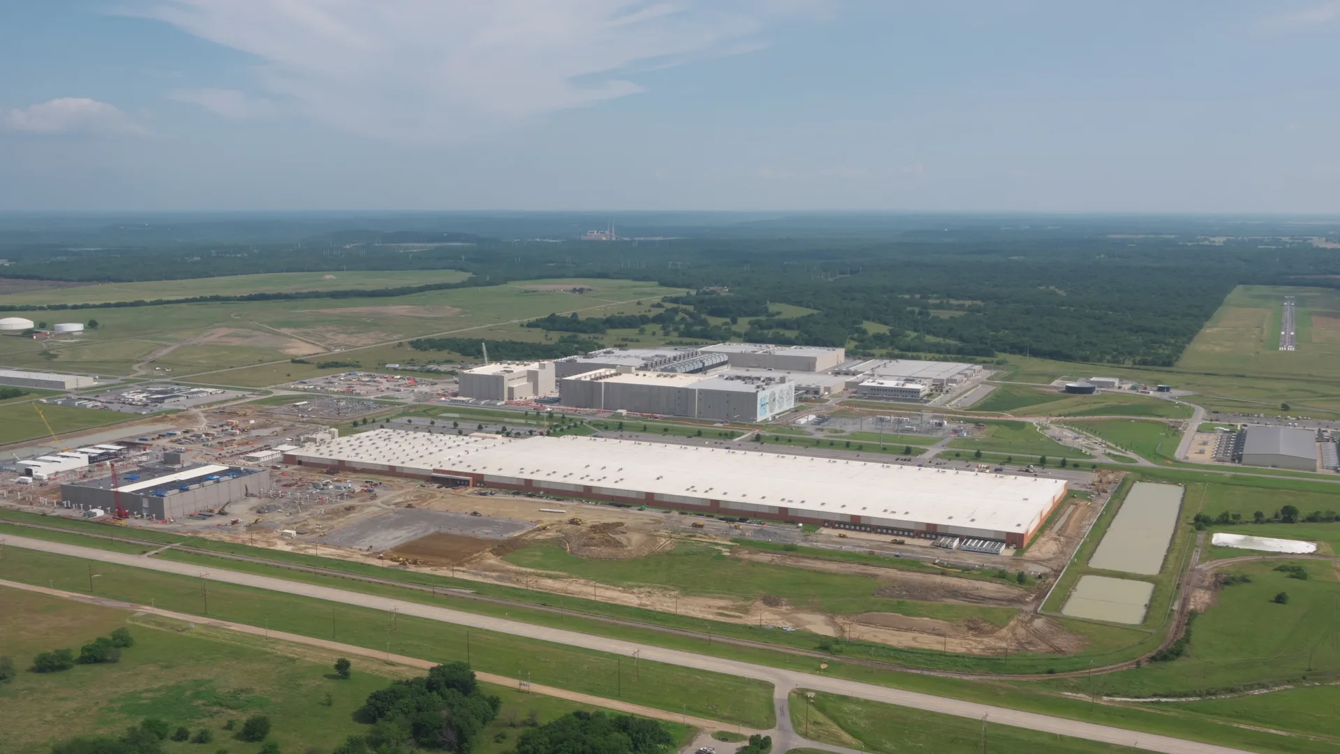 Aerial view of the Google data center campus outside Pryor, Oklahoma, with large white-roofed buildings surrounded by fields and trees.