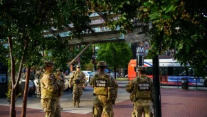 National Guard soldiers in camouflage and vests marked National Guard stand on a brick plaza outside the Eastern Market Metro station in Washington, D.C., during a September 2025 patrol.