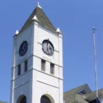 White clock tower of the Desha County Courthouse in Arkansas City against a blue sky.