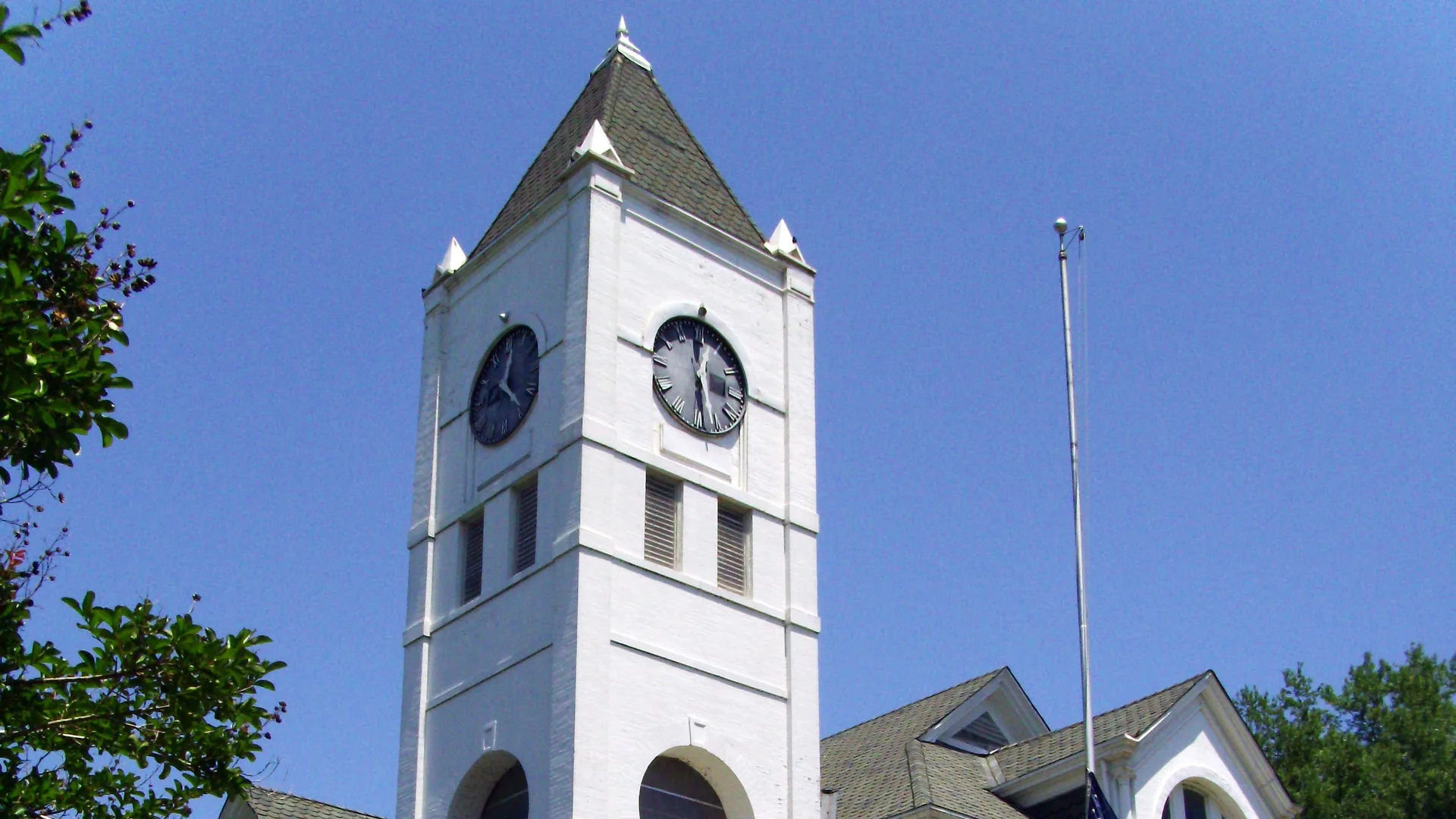 White clock tower of the Desha County Courthouse in Arkansas City against a blue sky.