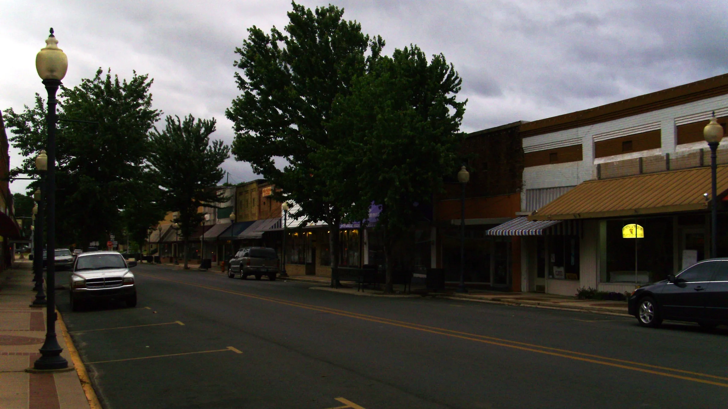 Main Street in downtown Warren, Arkansas, with storefronts and street lamps under a cloudy sky.