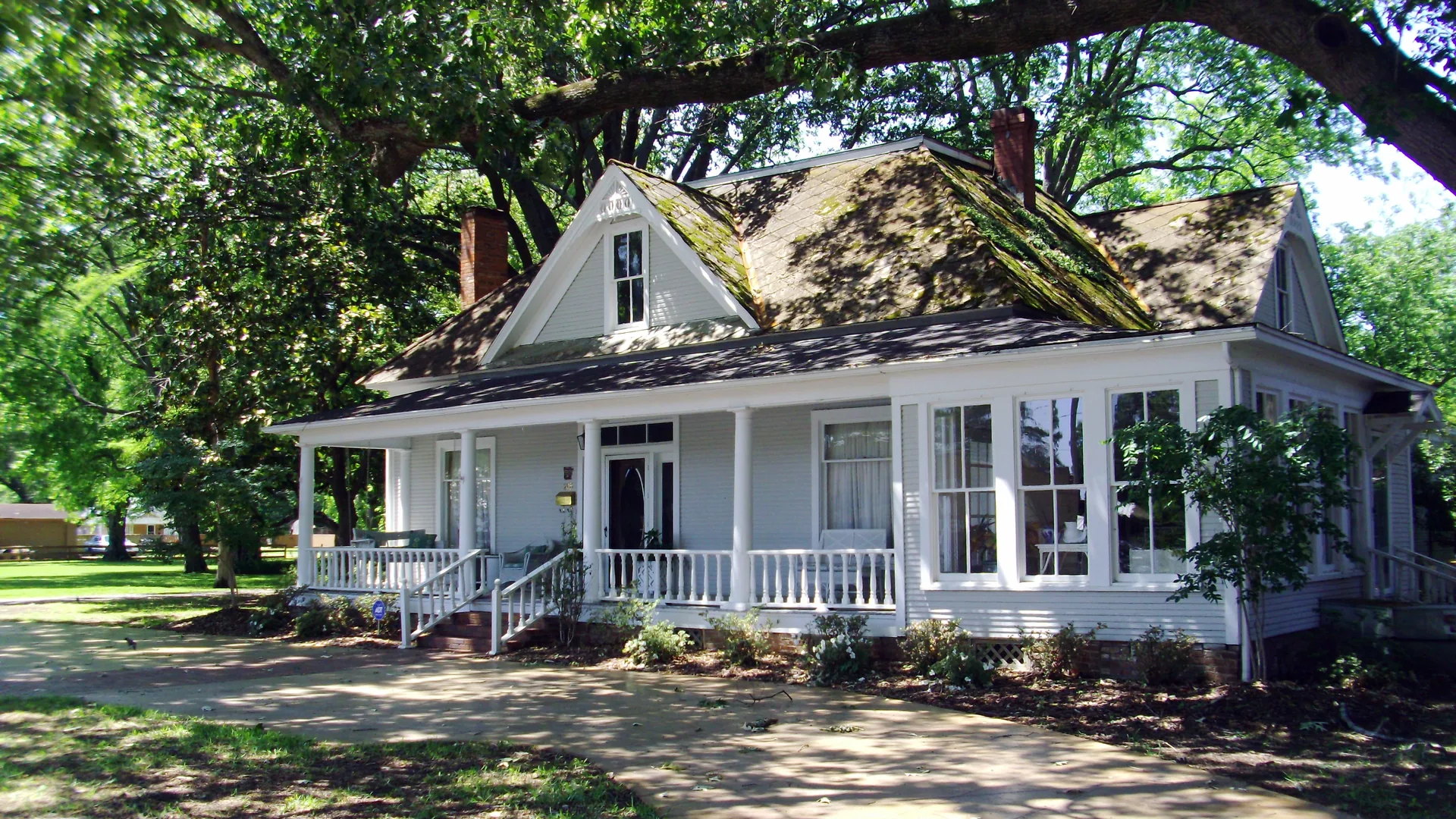 The historic McKennon-Shea House in Dumas, a white frame house with a front porch shaded by a large oak.