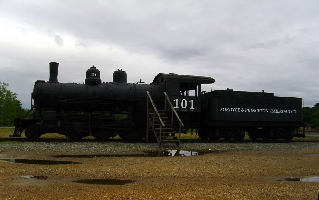 Black steam locomotive number 101 and its tender, lettered Fordyce and Princeton Railroad, on display on a short section of track.