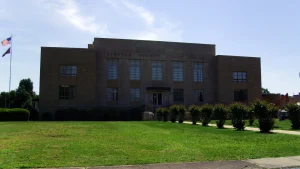 The Lincoln County Courthouse in Star City, Arkansas, a flat-roofed brick building behind a lawn and a row of shrubs