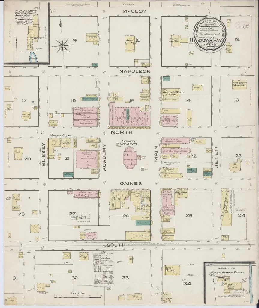 Hand-colored 1886 fire insurance map of downtown Monticello. The county courthouse sits alone in the middle of the block bounded by North, Main, Gaines and Academy streets, with rows of pink brick and yellow frame stores on the blocks around it.