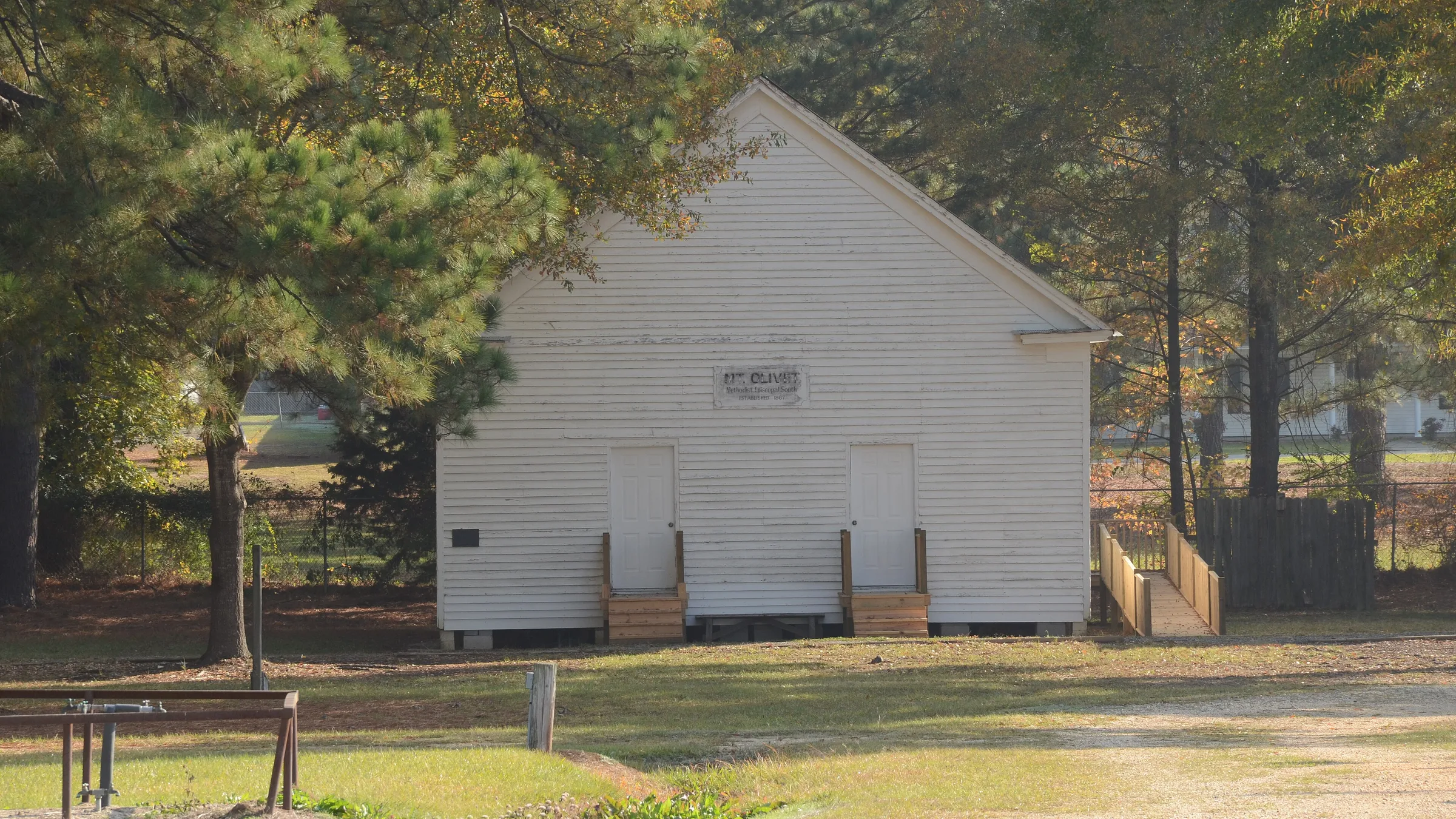 Mount Olivet Methodist Church, a white wooden church set back on a grassy lot in Cleveland County, Arkansas.