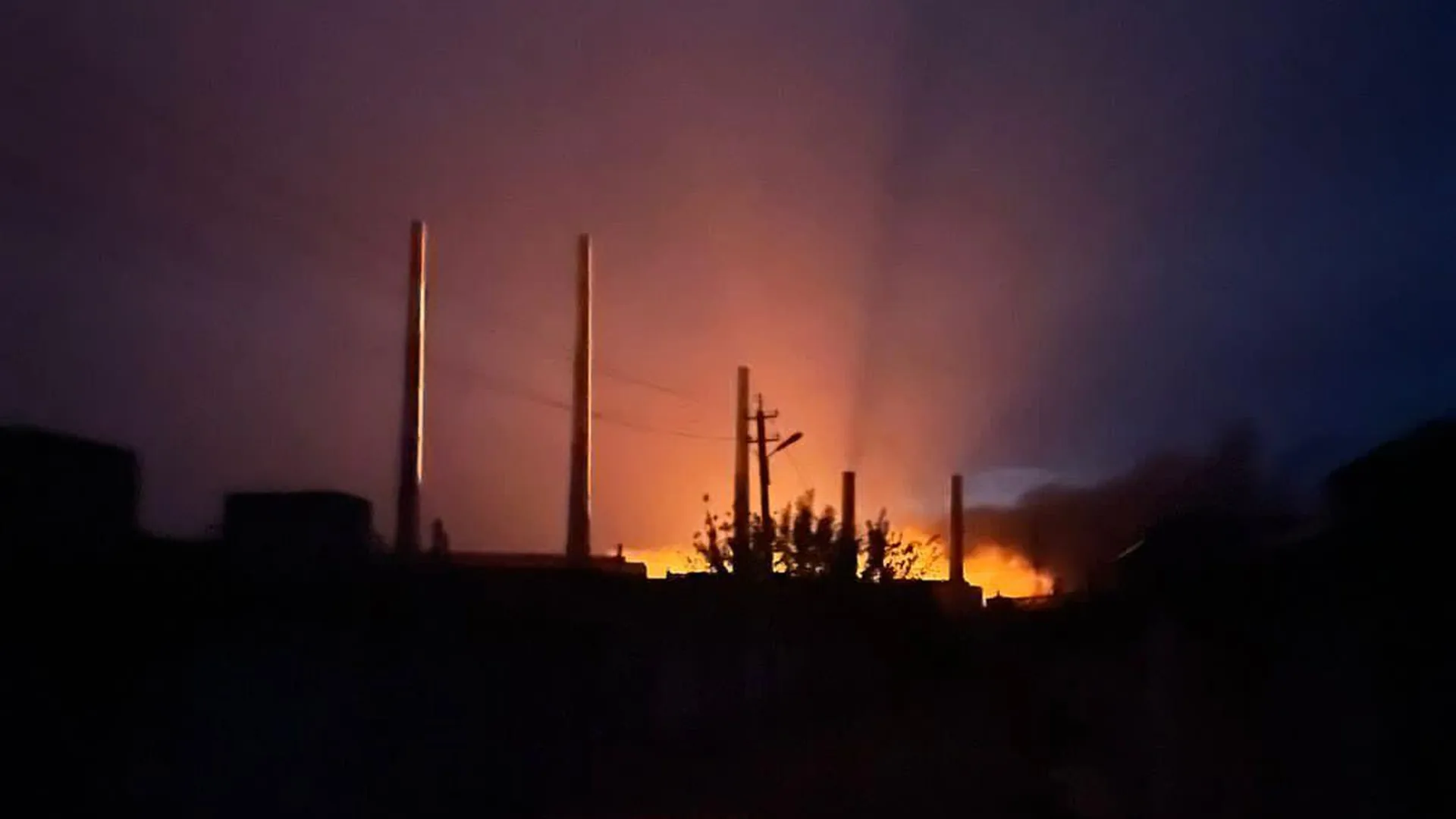 Fire glows behind the smokestacks of the Zmiiv thermal power plant in Ukraine's Kharkiv region at night after a Russian strike in September 2022