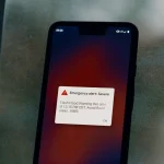 A smartphone screen showing a severe emergency alert for a flash flood warning from the National Weather Service.
