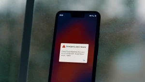 A smartphone screen showing a severe emergency alert for a flash flood warning from the National Weather Service.