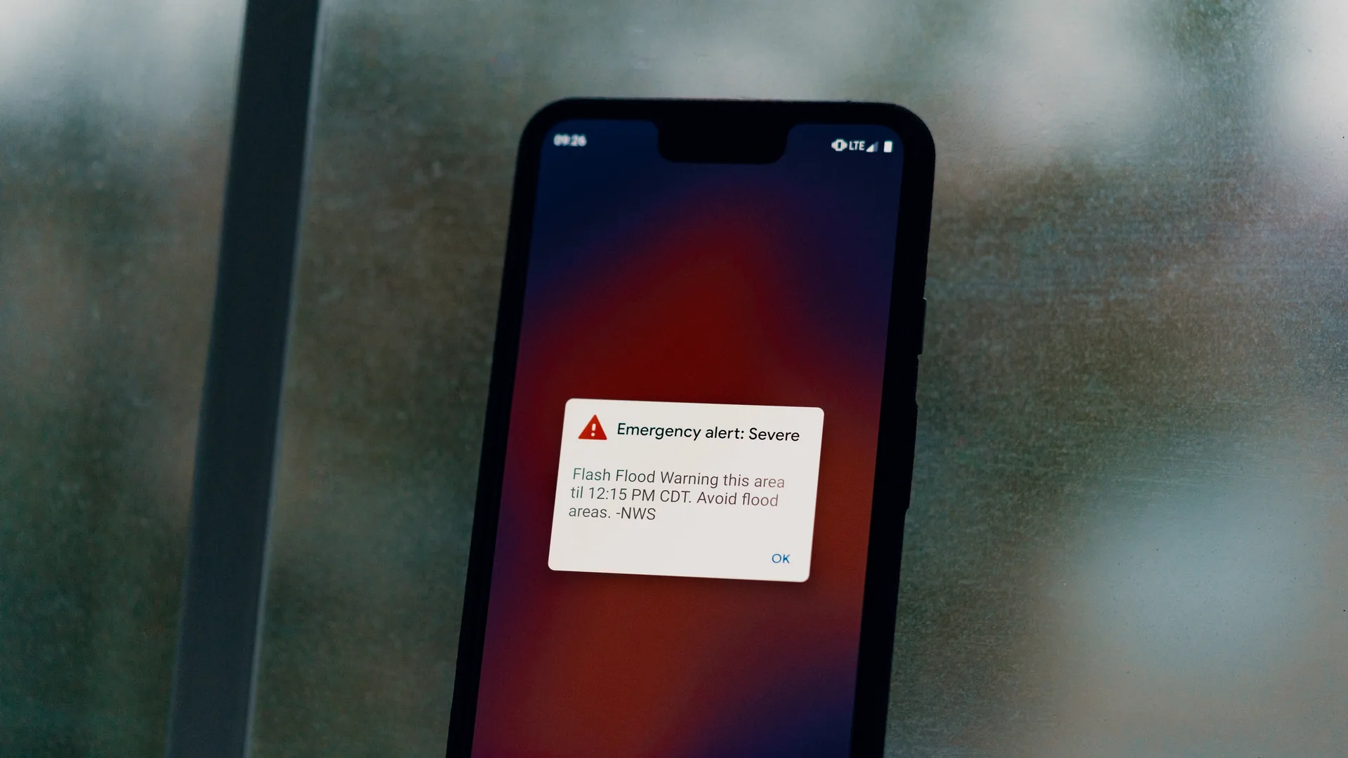 A smartphone screen showing a severe emergency alert for a flash flood warning from the National Weather Service.
