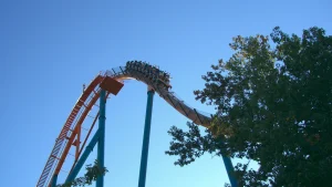 Riders on the Goliath roller coaster at Six Flags Over Georgia crest a hill against a blue sky