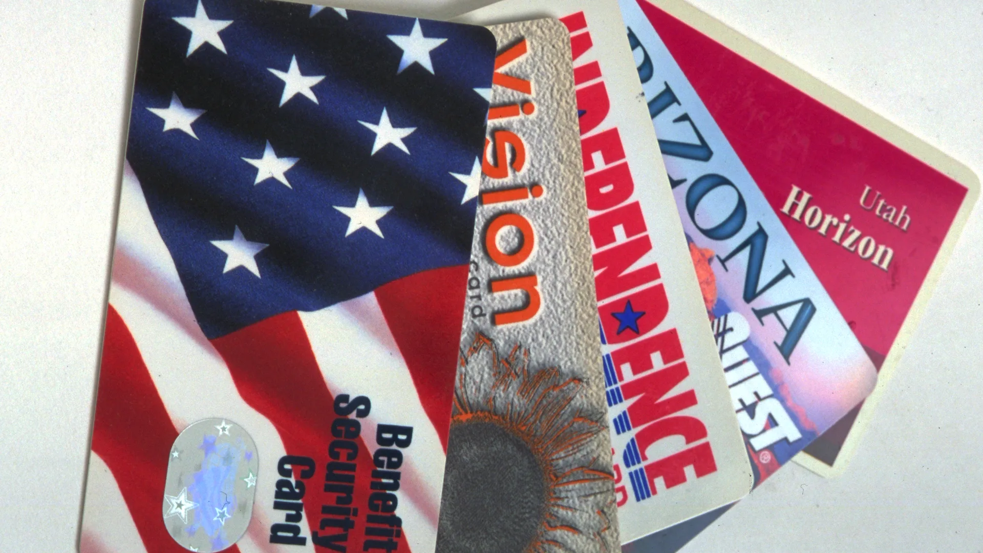 Electronic benefit transfer cards from several states fanned out on a table.