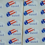 A sheet of oval "I Voted" stickers printed with a small American flag