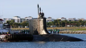 Sailors stand on the deck of the Virginia-class submarine USS Texas as a tugboat guides it into port near Port Canaveral, Florida