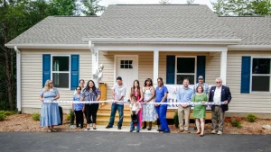 Group cutting a ribbon in front of a new single-story home with blue shutters, built with a USDA Rural Development direct home loan in North Carolina.