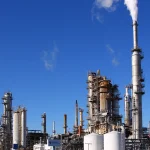 The Valero oil refinery in Three Rivers, Texas, with distillation towers, storage tanks and a tall smokestack under a blue sky.