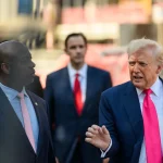 President Donald Trump speaks to reporters beside Sen. Tim Scott outside the Federal Reserve in Washington in July 2025.