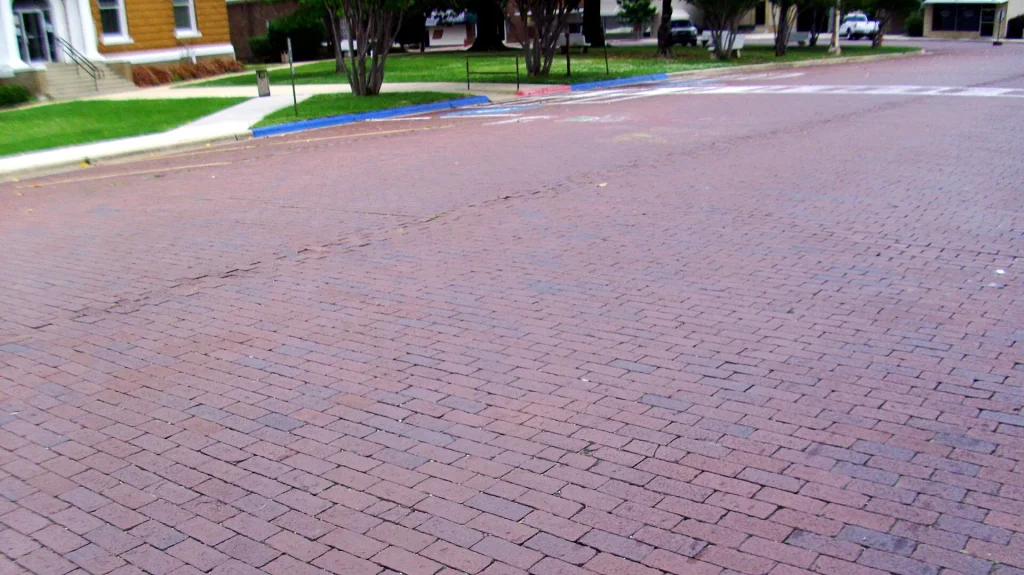 A red brick-paved street running past the courthouse lawn.