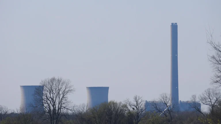 The cooling towers and tall smokestack of Entergy Arkansas's White Bluff power plant in the haze beyond bare trees.
