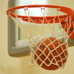 Basketball dropping through an orange rim and net