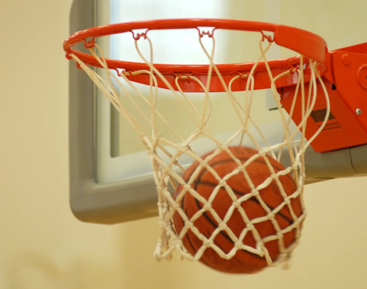 Basketball dropping through an orange rim and net