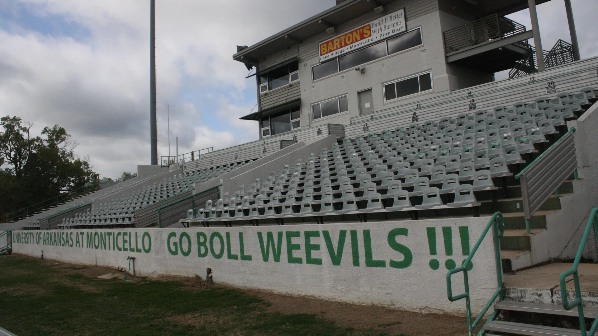 The home grandstand and press box at Willis "Convoy" Leslie Cotton Boll Stadium in Monticello, Arkansas, with GO BOLL WEEVILS painted on the wall.