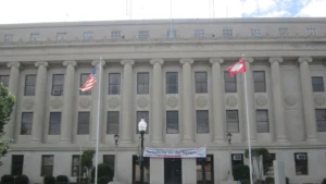 Union County Courthouse in El Dorado, Arkansas: a light stone building with a long row of tall columns and the words UNION COUNTY COURTHOUSE carved above them, with U.S. and Arkansas flags out front.