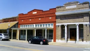 A row of historic storefronts along Main Street in downtown Dumas, Arkansas, including a three-story red-brick building with arched windows.