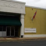 A tan brick commercial building with a green awning reading FIRST STATE BANK in downtown Warren, Arkansas.