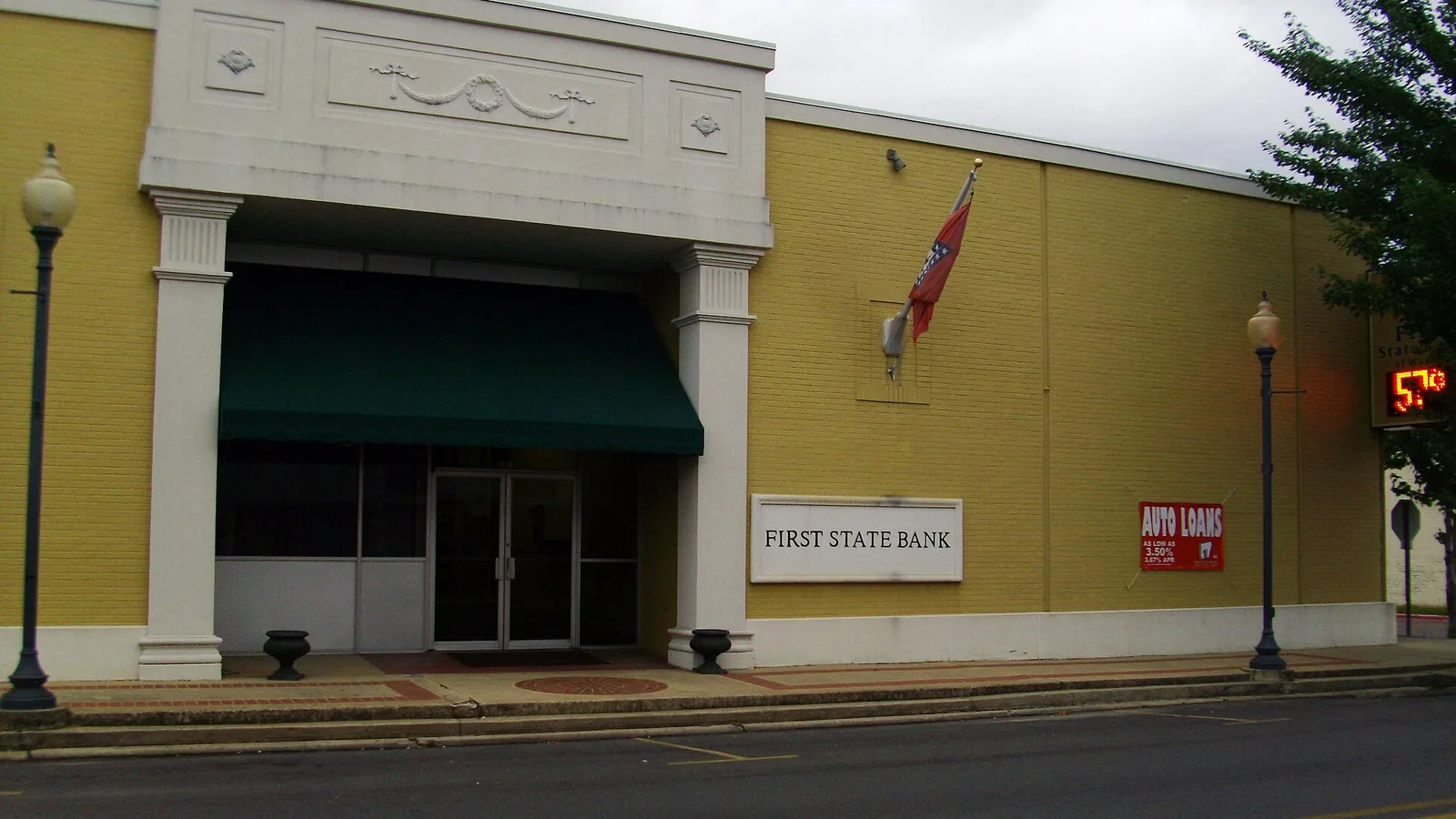 A tan brick commercial building with a green awning reading FIRST STATE BANK in downtown Warren, Arkansas.