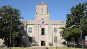The El Dorado Municipal Building in Arkansas, a tall stone Art Deco-style building with a central clock tower and an American flag out front.
