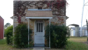The small stone building that served as Hermitage, Arkansas, city hall and jail, with one white door and one window, surrounded by grass.
