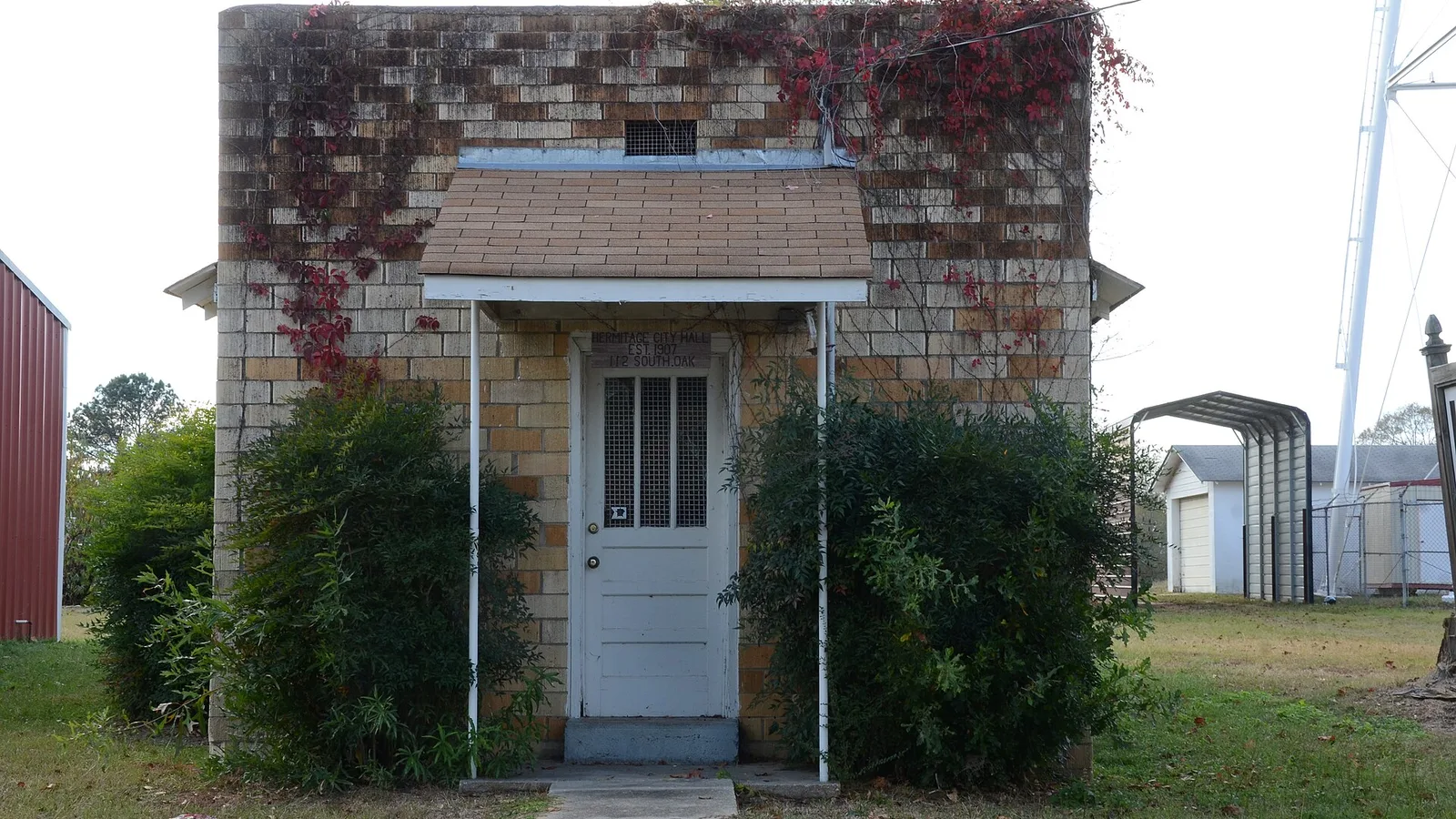 The small stone building that served as Hermitage, Arkansas, city hall and jail, with one white door and one window, surrounded by grass.