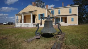 Lakeport Plantation in Chicot County near Lake Village, Arkansas, a two-story yellow house with blue shutters and a large iron bell on the lawn.