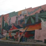 A large multi-colored mural painted on the side of a brick building in downtown Monticello, Arkansas.