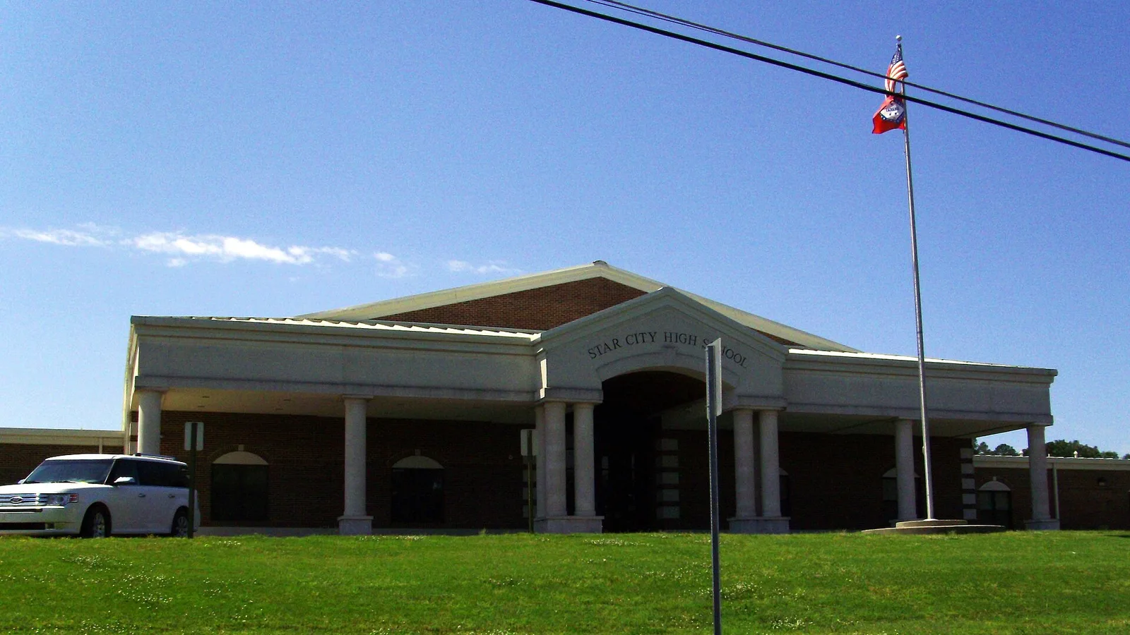 Star City High School in Arkansas, a one-story brick building with white columns at the entrance, seen across the lawn from Highway 11.