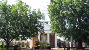 The Grant County Courthouse in Sheridan, Arkansas, a white building with a central clock tower among trees.