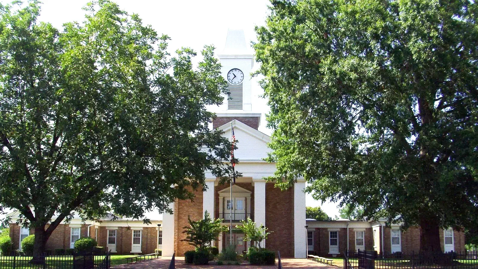 The Grant County Courthouse in Sheridan, Arkansas, a white building with a central clock tower among trees.