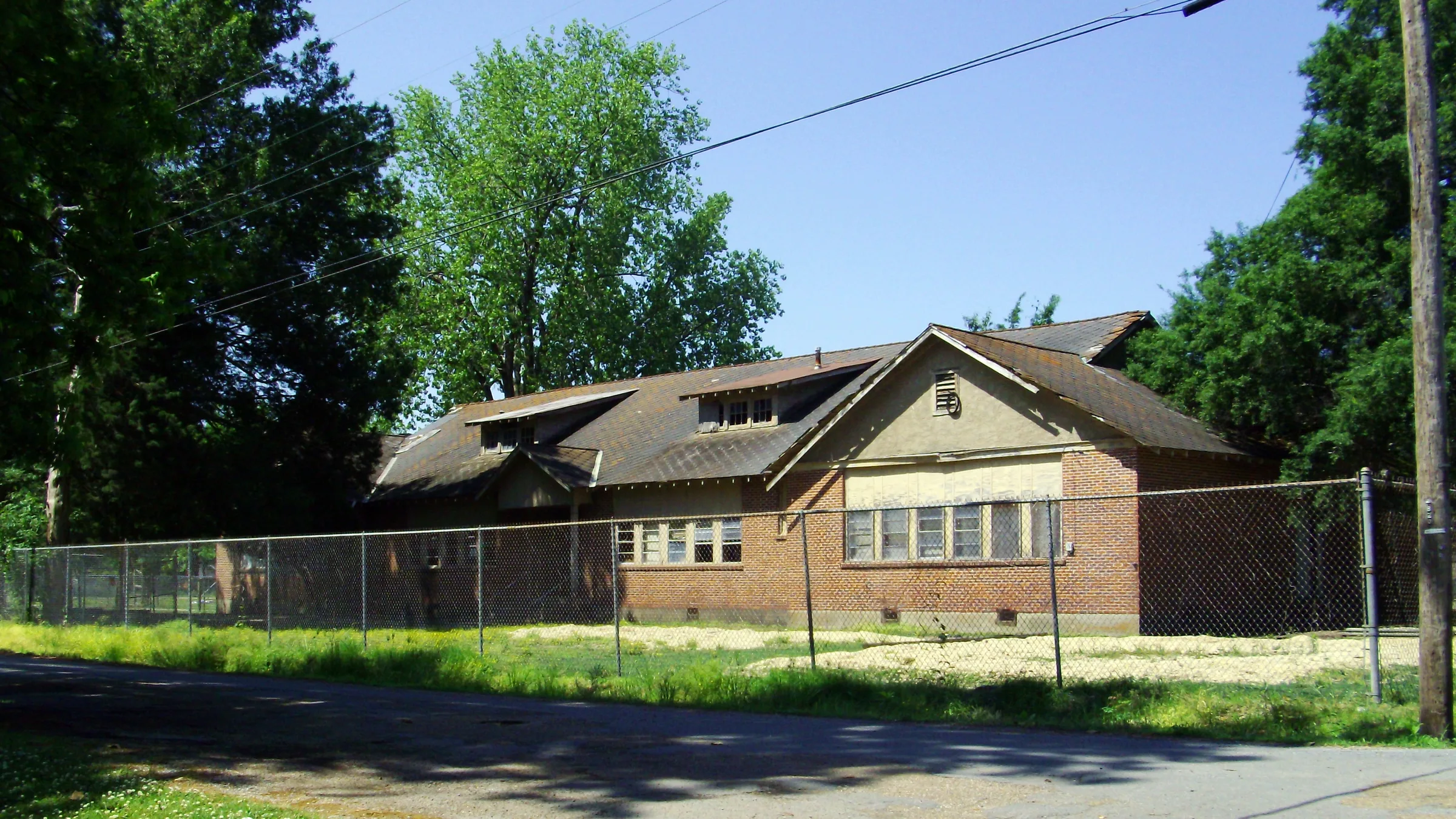 The Chicot County Training School in Dermott, Arkansas, a long single-story red-brick building with several gables, behind a chain-link fence and under large trees.