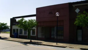 An older red-brick commercial building with a glass storefront and a round street lamp in downtown Dermott, Arkansas.