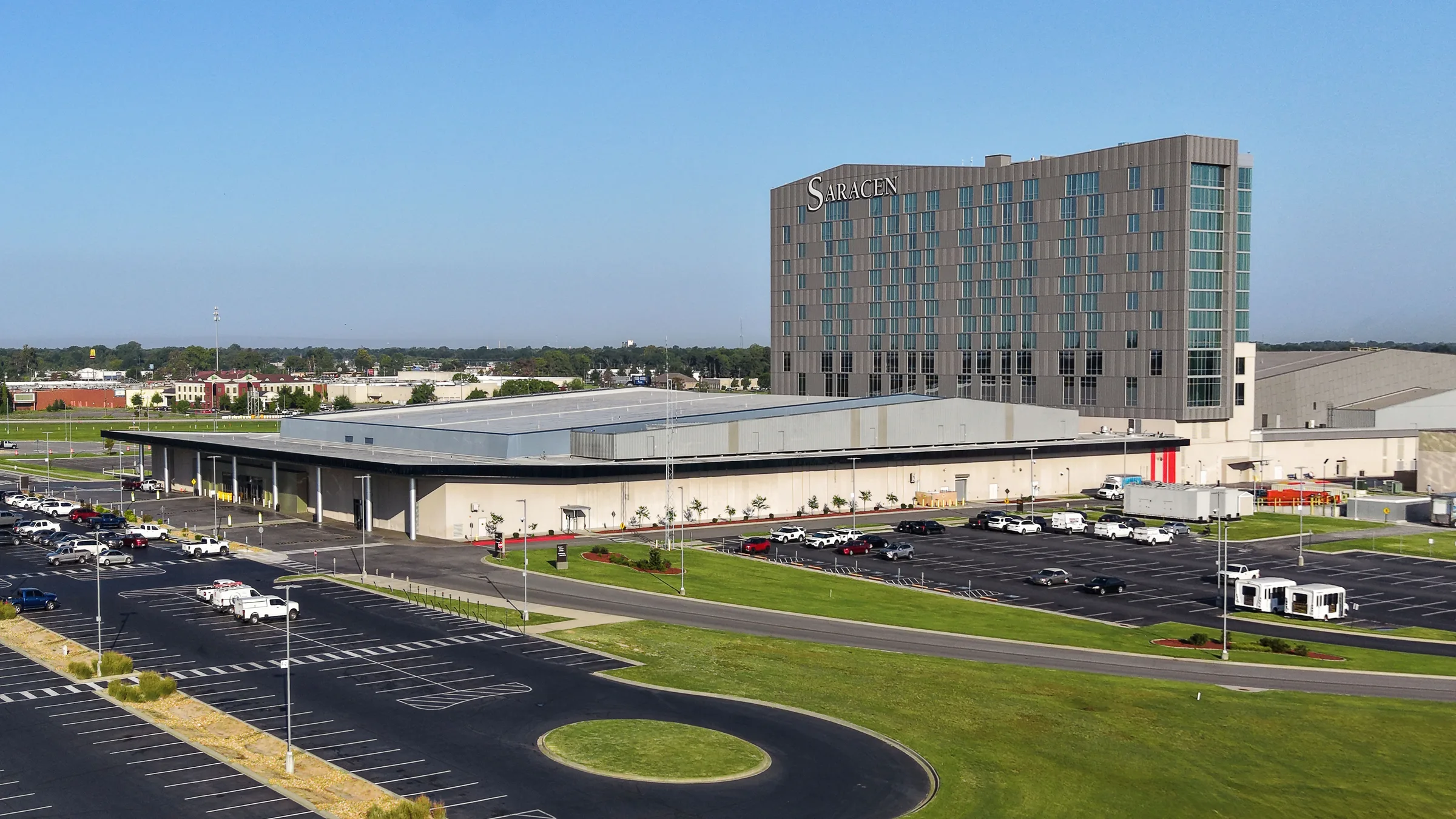 Saracen Casino Resort in Pine Bluff, Arkansas, a tall hotel tower beside a wide event and gaming building with a large parking lot in front.