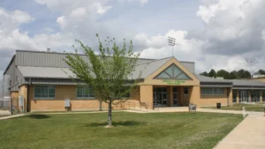 Gibson University Center on the University of Arkansas at Monticello campus, a tan building with an angled metal roof and the center name on the front.